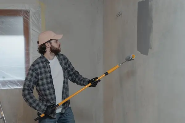 Painter rolling grey paint onto an interior wall in Syracuse