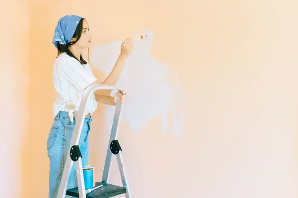 Interior painting in Syracuse: painter on a stepladder rolling a wall